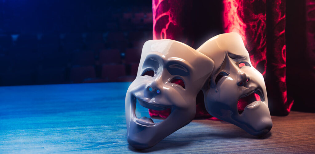 Theater masks, drama and comedy with a red curtain as backdrop. (iStock) 