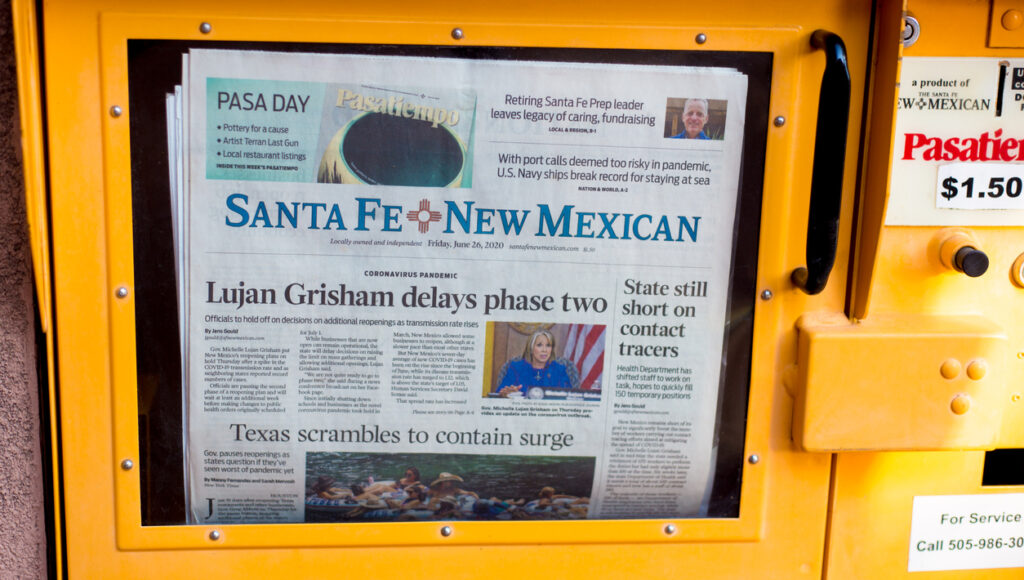 Santa Fe, NM: A Santa Fe New Mexican newspaper vending machine in downtown Santa Fe with headlines related to a COVID-19 surge in Texas and a reopening delay in New Mexico.
