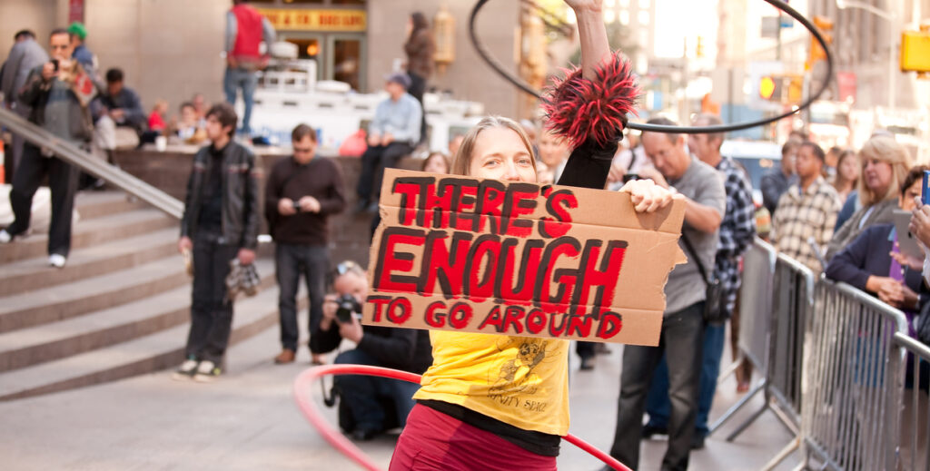 New York City, New York, USA - October 6, 2011: A woman hula-hooping and holding a protest sign to raise awareness at Occupy Wall Street in Zuccotti Park.
