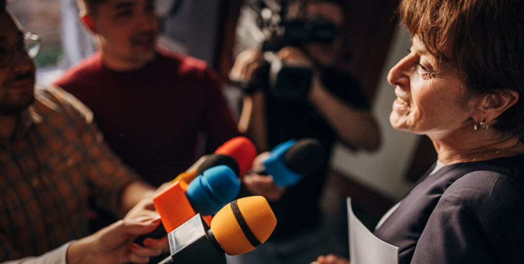 Politician confronted by journalists with microphones.