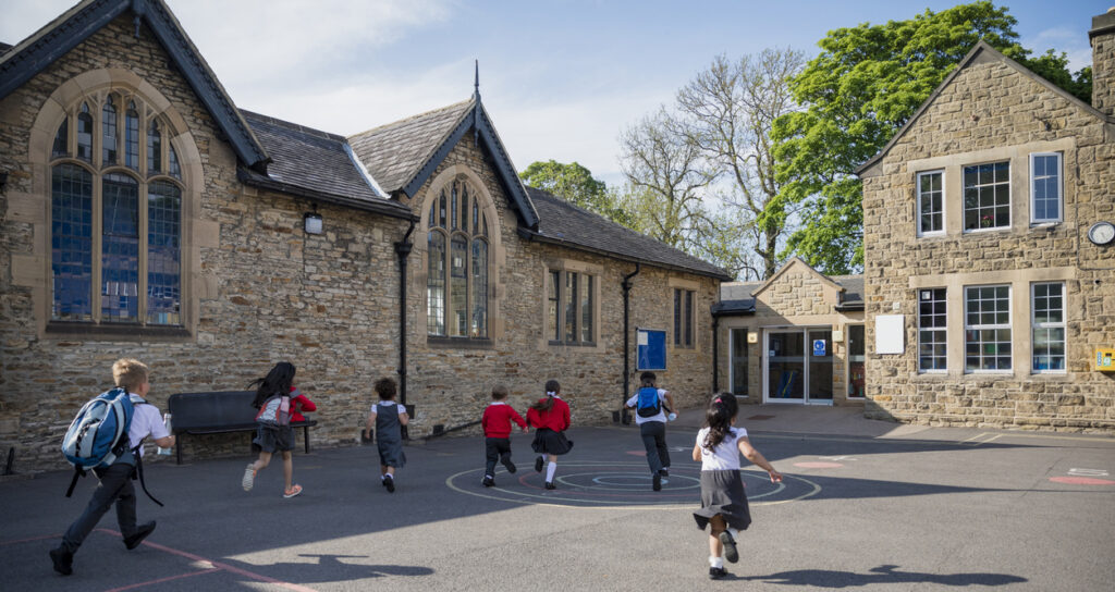 Rear view of children running in their school yard in the North East of England. 